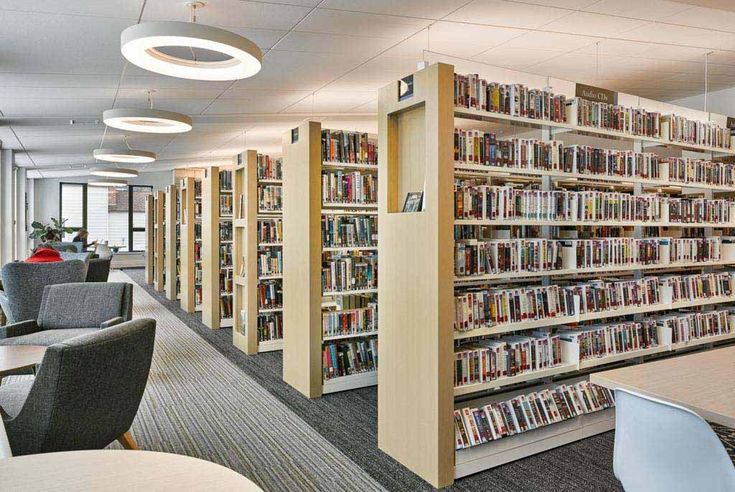 the library is full of books and chairs for people to sit down at their desks