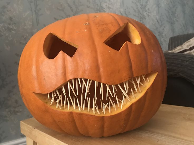 a carved pumpkin with spikes on it's face and mouth is sitting on a table