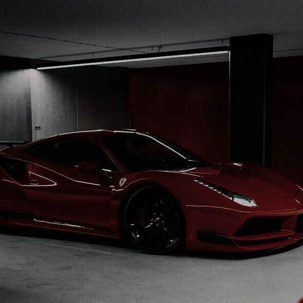 a red sports car parked in a parking garage with its door open and lights on