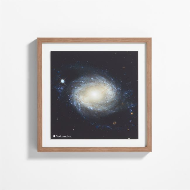 a framed photograph of the andromidus galaxy, taken from above it is mounted on a wall