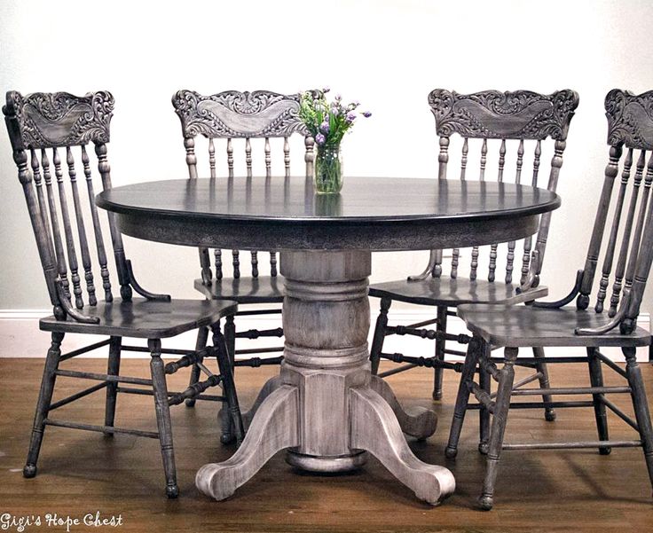 a table with four chairs around it and a vase filled with flowers on the top