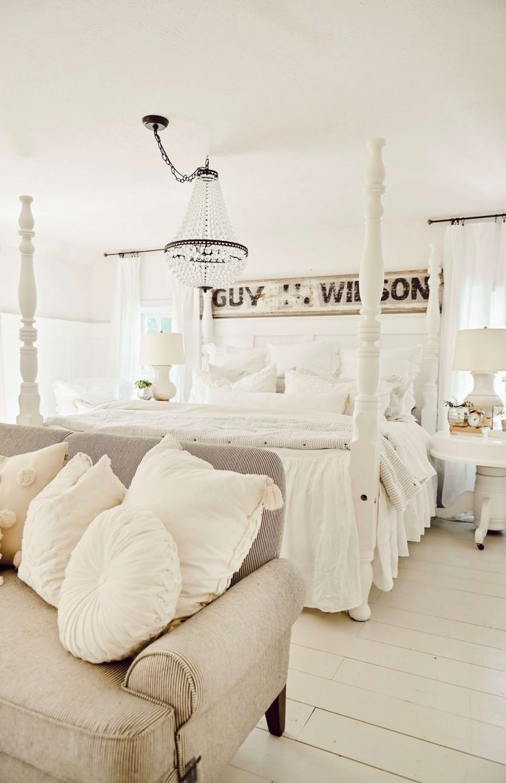 a white bed sitting in a bedroom next to a couch with pillows on top of it