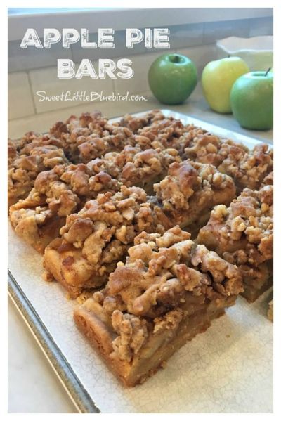 apple pie bars are cut into squares and placed on a baking sheet with apples in the background