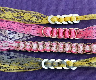 three different colored lace belts on a purple cloth background with white and yellow trimmings