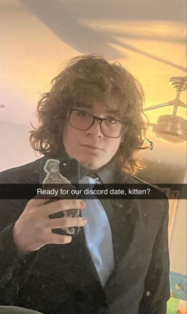 a man in a suit and tie holding a cell phone with the caption ready for our discord date, kittenen?