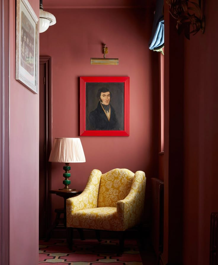 a living room with a chair, lamp and painting on the wall in it's corner