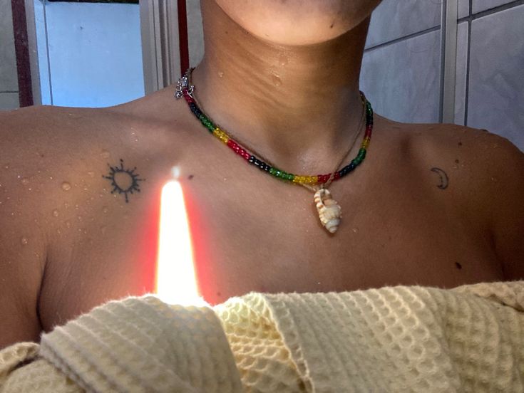 a woman holding a lit candle in front of her chest with the sun on it