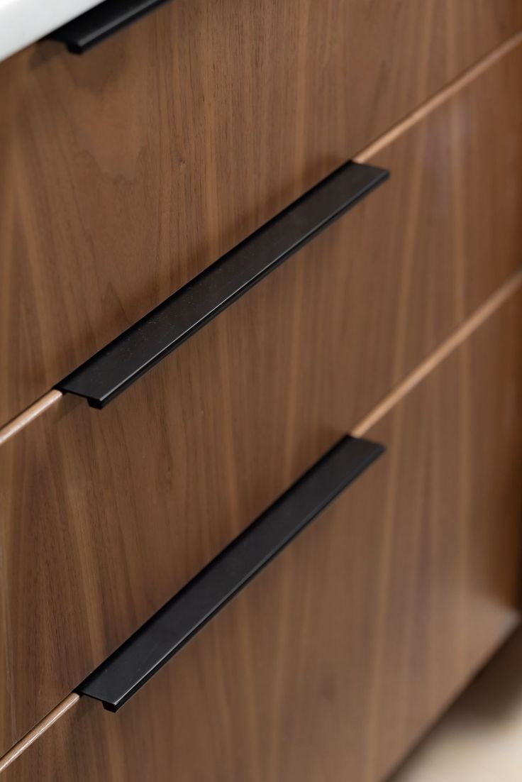 a close up of a wooden cabinet with black handles