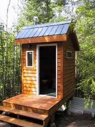 a tiny cabin in the woods with stairs leading up to it and a door open