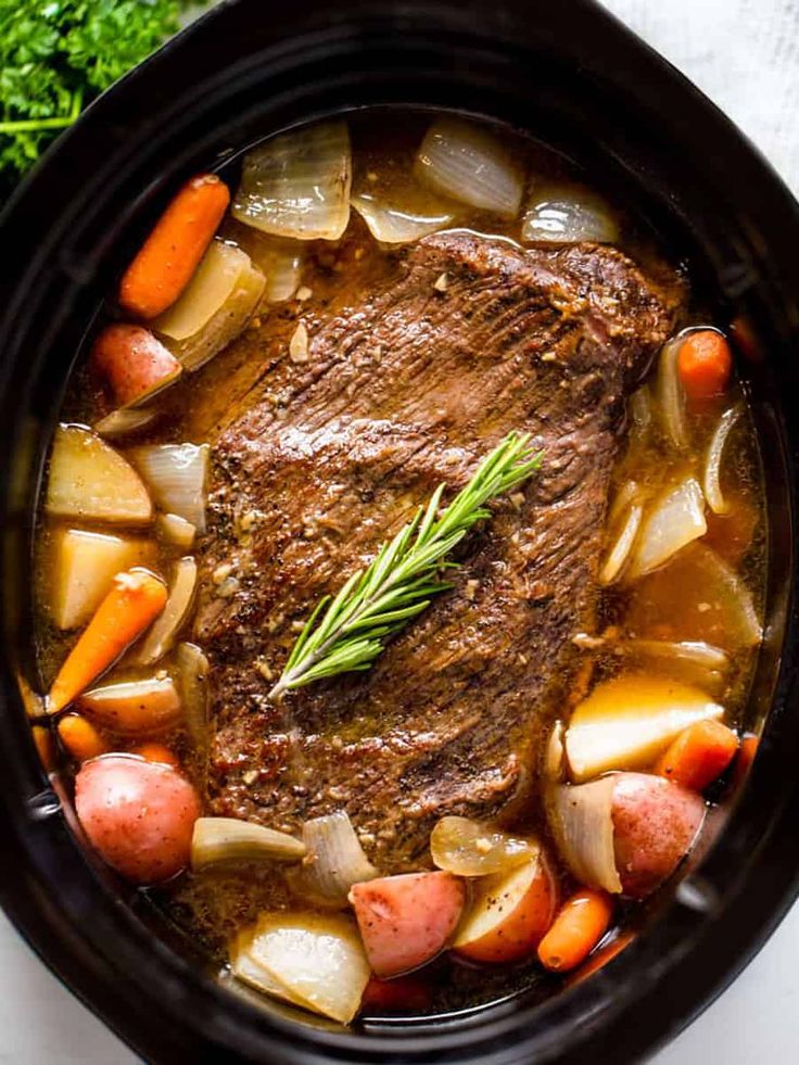 a pot roast with carrots, potatoes and parsley on the side is ready to be eaten