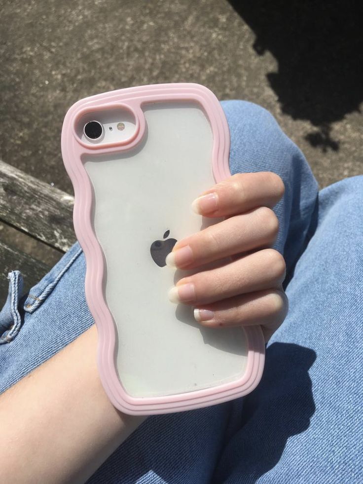 a person is holding an iphone case in their left hand and sitting on the ground