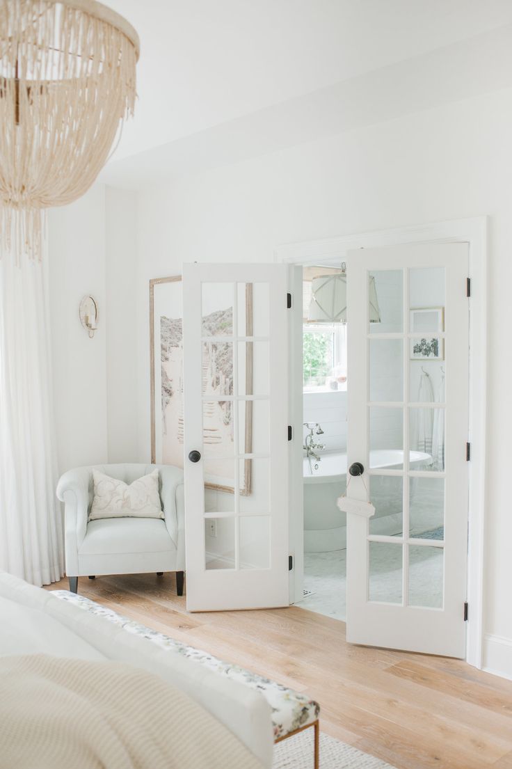 a bedroom with french doors and white furniture