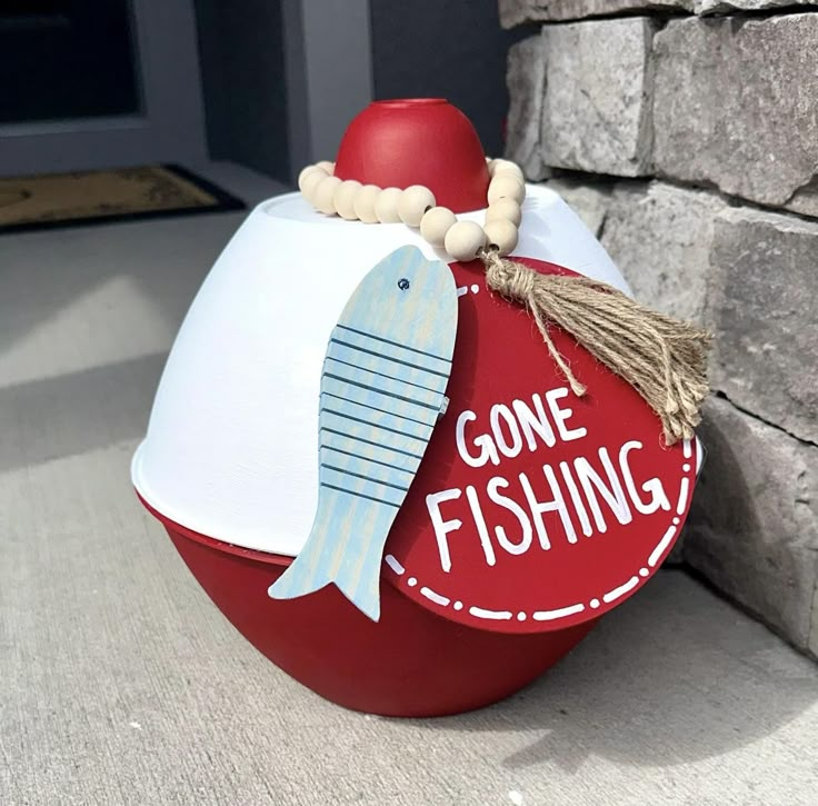 a red and white fish shaped container sitting on the side of a brick wall next to a door