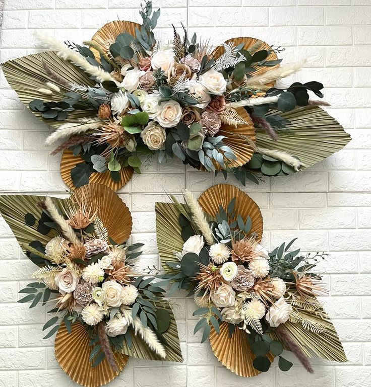 three decorative wall hangings with flowers and leaves on the side of a brick wall