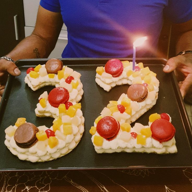 a man holding a tray with some type of cake in the shape of the number 50