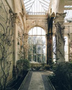 an old building with many windows and plants in the middle of it's walkway