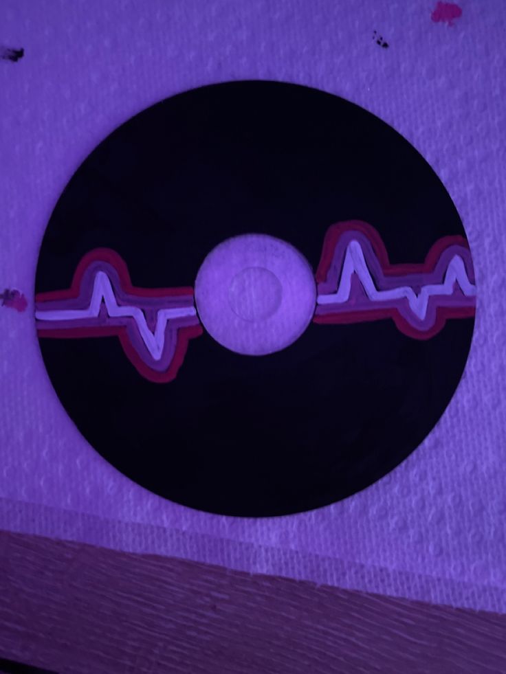 a black record with red and white lines on the side in front of a purple background