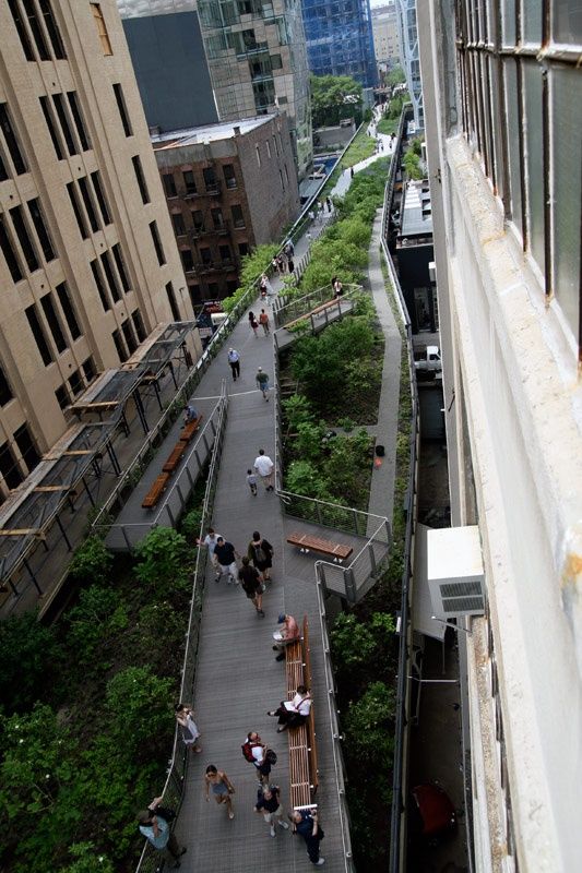 people are walking down an elevated walkway in the city