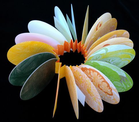 a colorful flower made out of paper on a black background