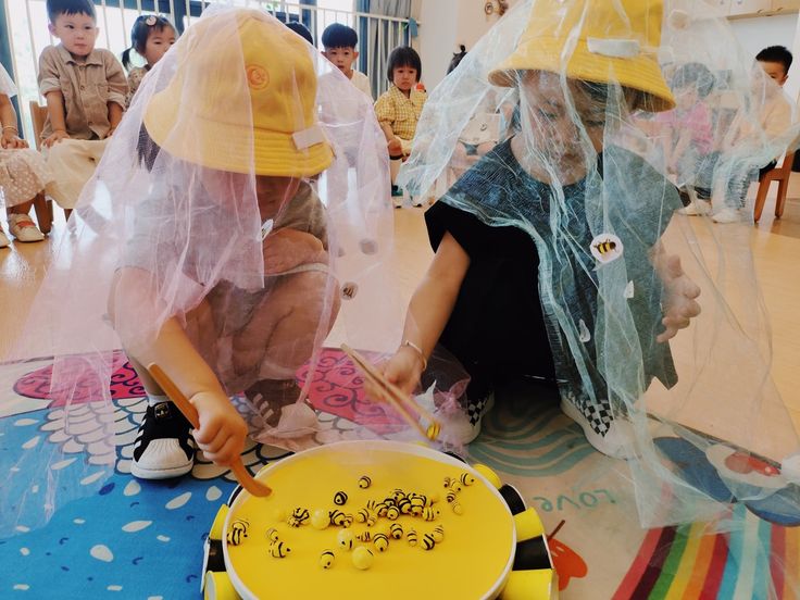 two children are sitting on the floor and one child is playing with a yellow cake