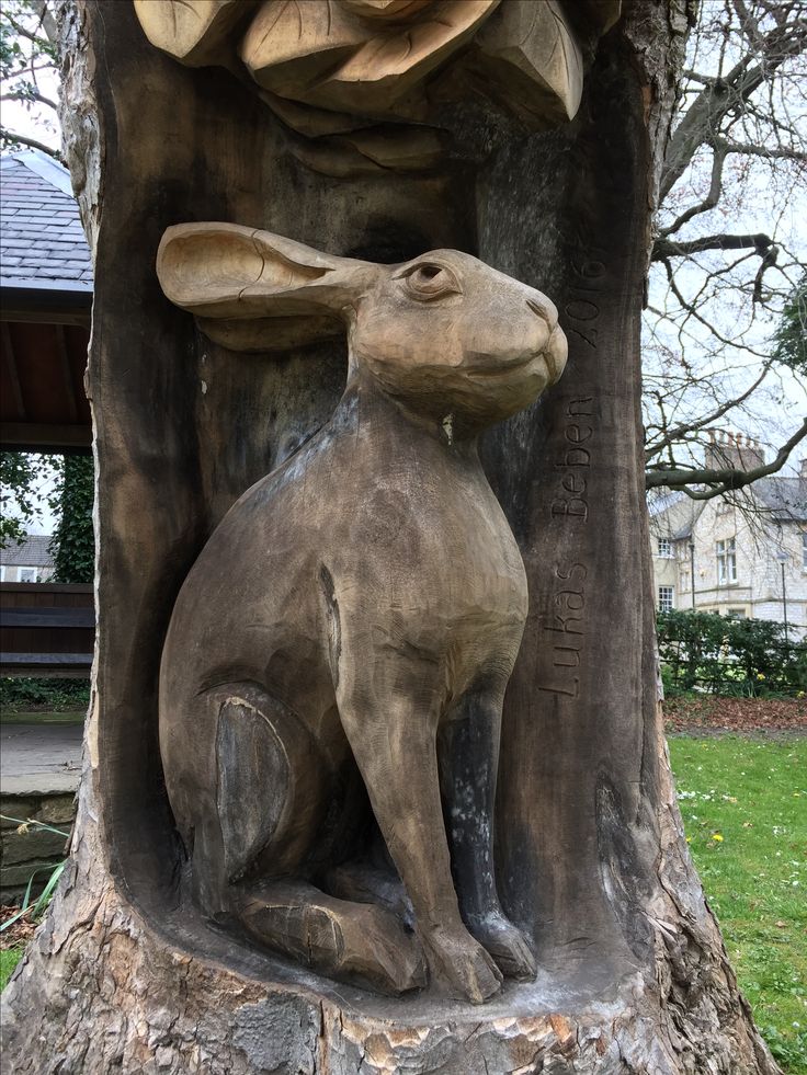 a statue of a rabbit sitting next to a tree