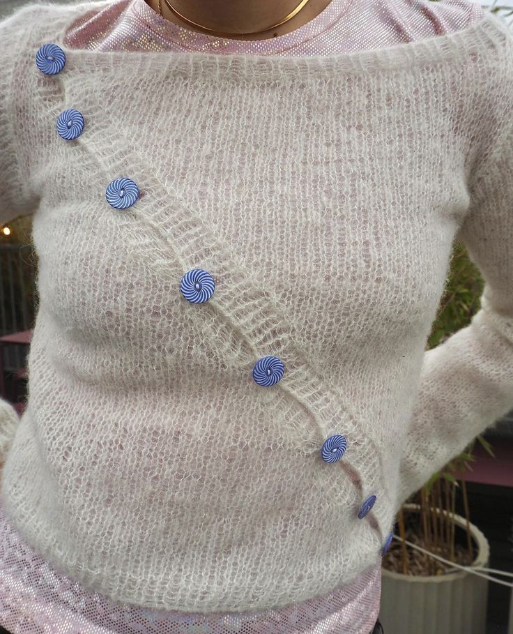 a close up of a person wearing a sweater with blue buttons on the front and back