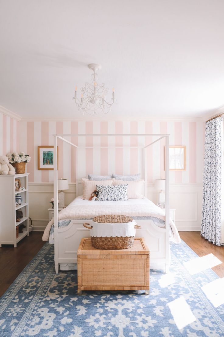 a bedroom with pink and white stripes on the walls, a blue rug and a wicker basket