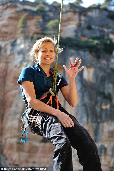 a woman hanging from a rope with her hands in the air and smiling at the camera