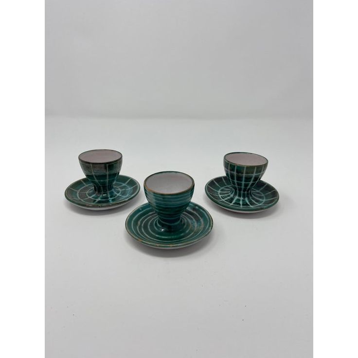 three green cups and saucers on a white surface