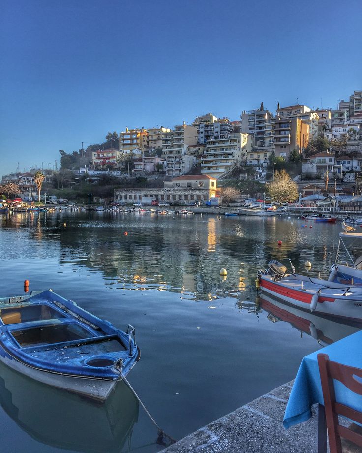 boats are docked in the water next to some houses and buildings on top of a hill