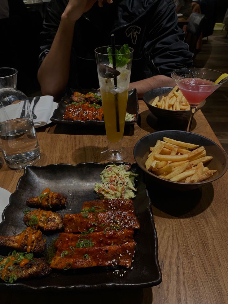 a man sitting at a table with plates of food and drinks in front of him