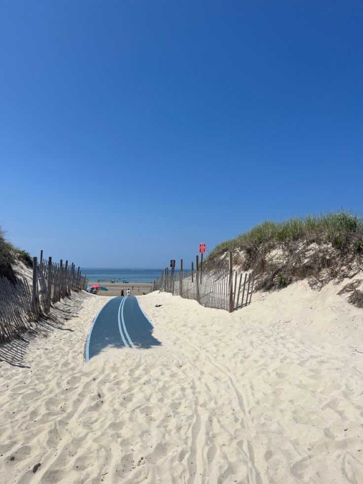 an empty beach with sand, fence and ocean in the background