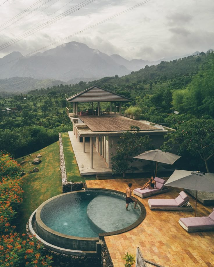 an outdoor hot tub in the middle of a wooden deck with chaise lounge chairs and umbrellas