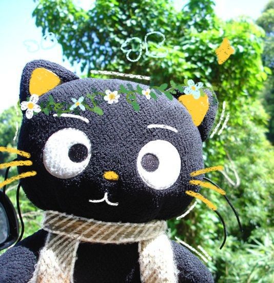 a black cat stuffed animal with flowers on it's head