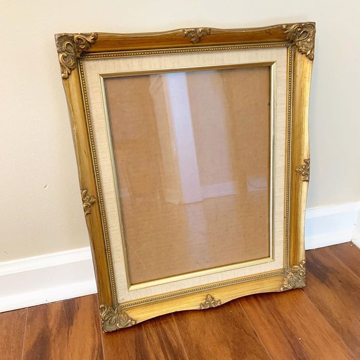 an old gold frame sitting on top of a hard wood floor