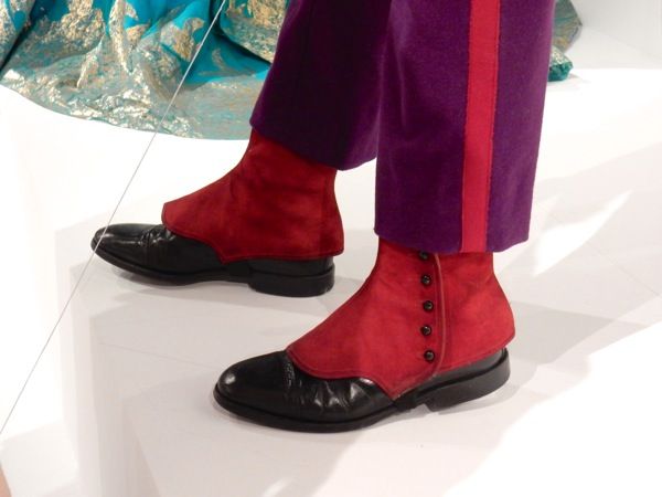 a person wearing red and purple pants with black shoes on the runway at a fashion show