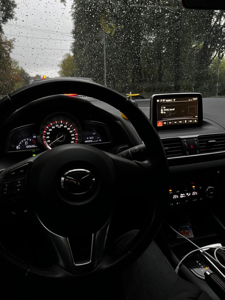 the interior of a car with dashboard, steering wheel and dash lights in the rain