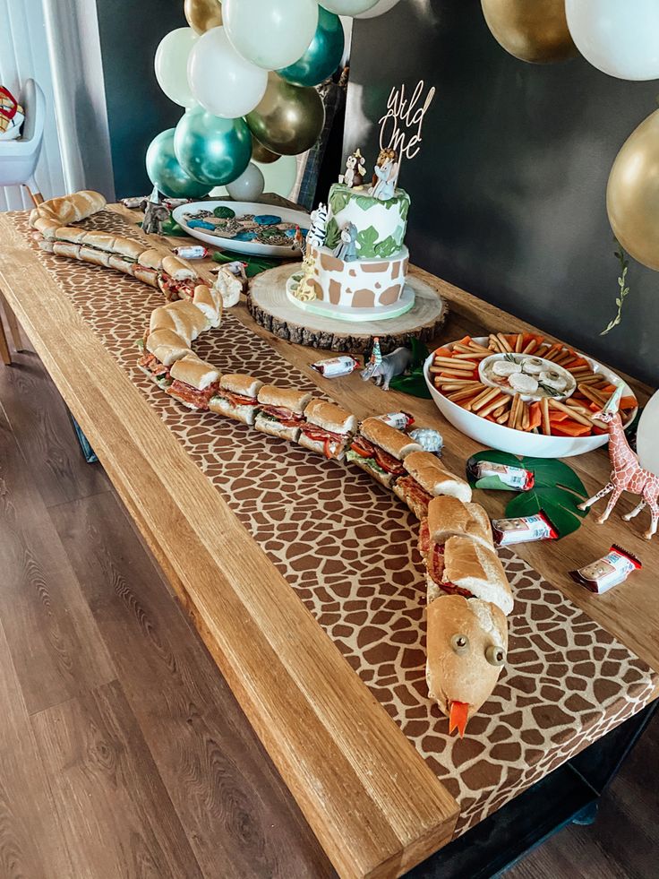 a table topped with cake and balloons in the shape of giraffe's head