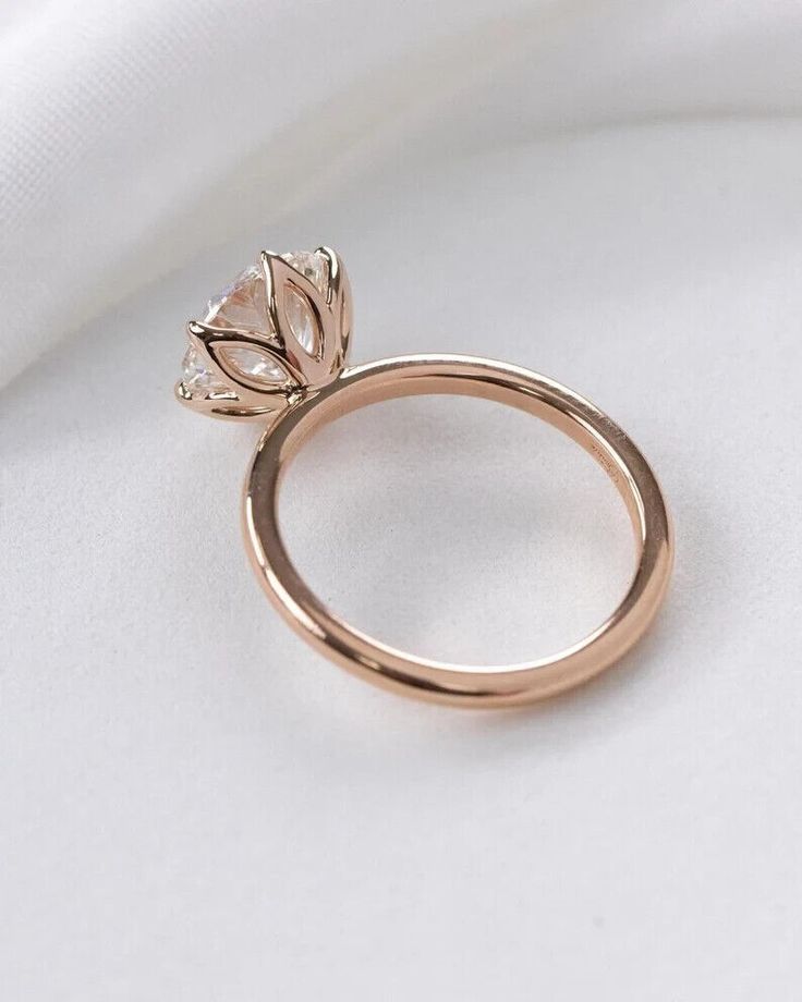 a rose shaped diamond ring on top of a white cloth