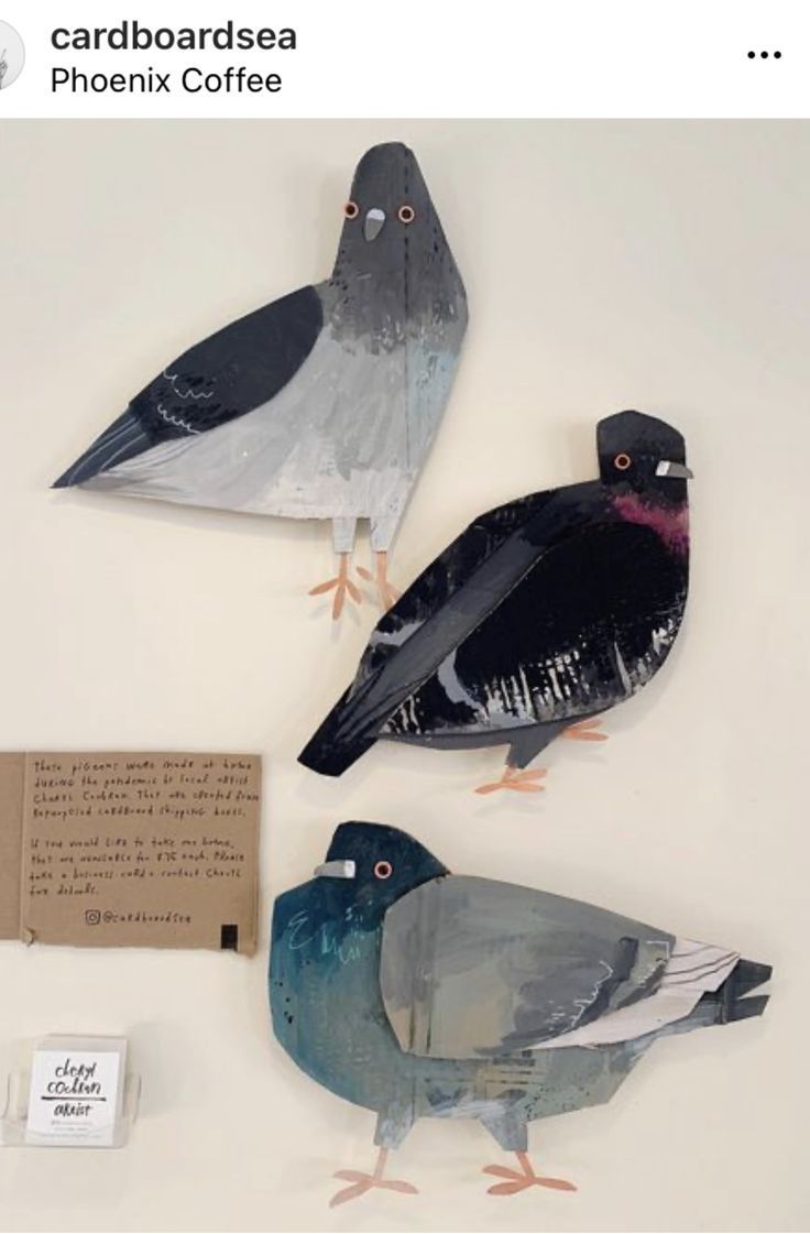 three birds sitting on top of a white table next to a card board and envelope