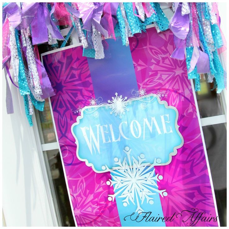 a welcome sign hanging from the side of a window with ribbons and streamers around it