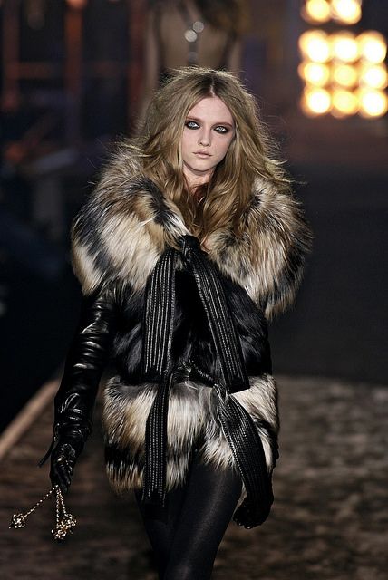 a woman walking down a runway wearing black and white fur