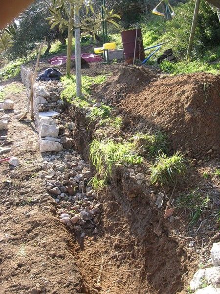 a pile of dirt sitting next to a lush green hillside