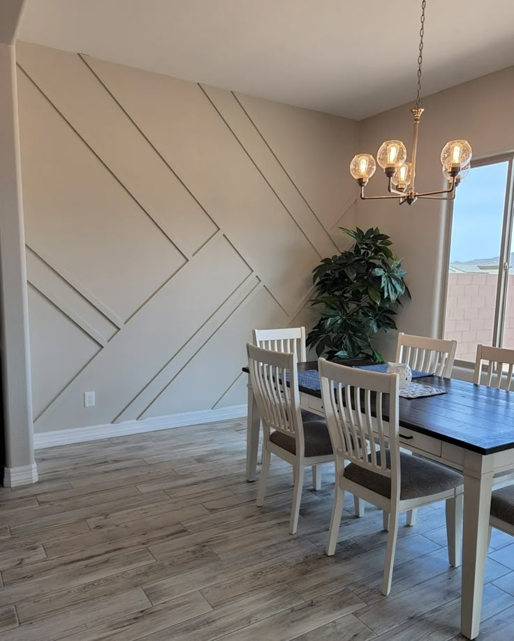 a dining room table with four chairs and a potted plant in the corner next to it