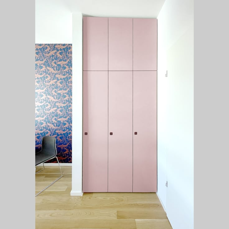 an empty room with pink cupboards and blue wallpaper