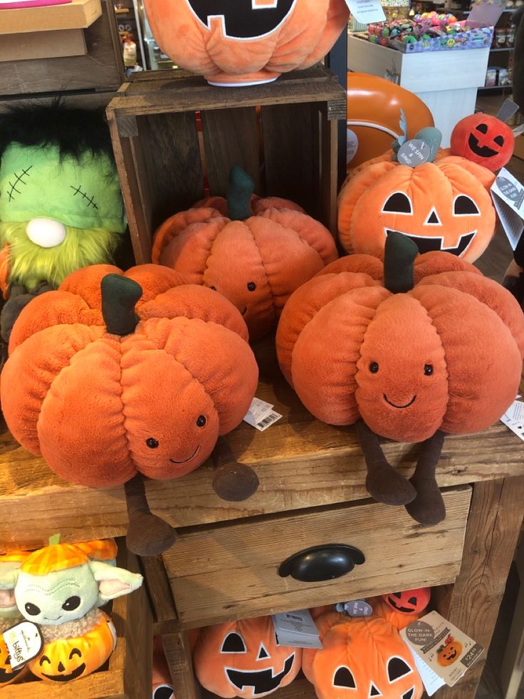 several pumpkins with faces on them sit in front of a wooden box filled with stuffed animals