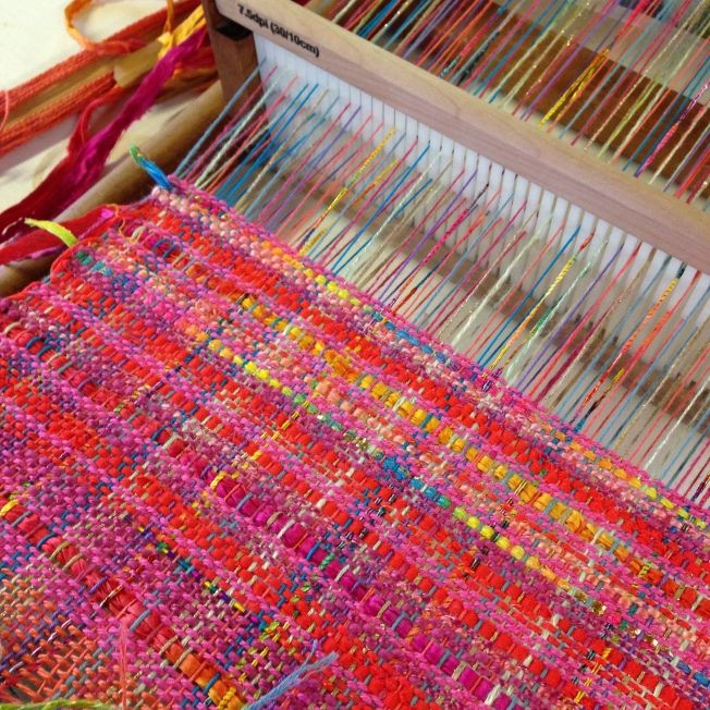 the weaving machine is being used to weave colorful yarn on it's loom