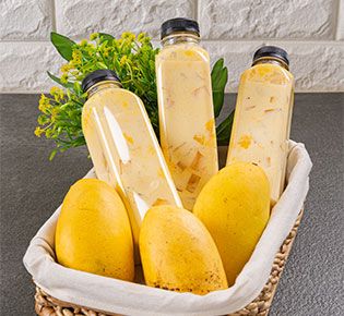 a basket filled with bottles and mangoes on top of a counter next to a plant