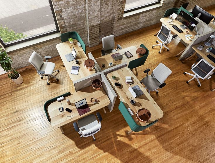 an overhead view of office desks with computers and laptops on them, in the middle of a wood floored room