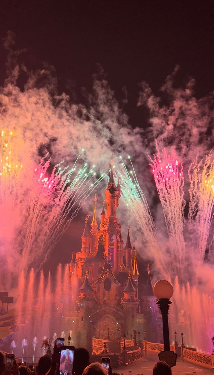 fireworks light up the night sky in front of disney's castle at disneyland world